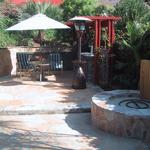 The area is built as a an outdoor kitchen with appliances under the red pergola and a fire pit is being added for cozy evening entertainment.